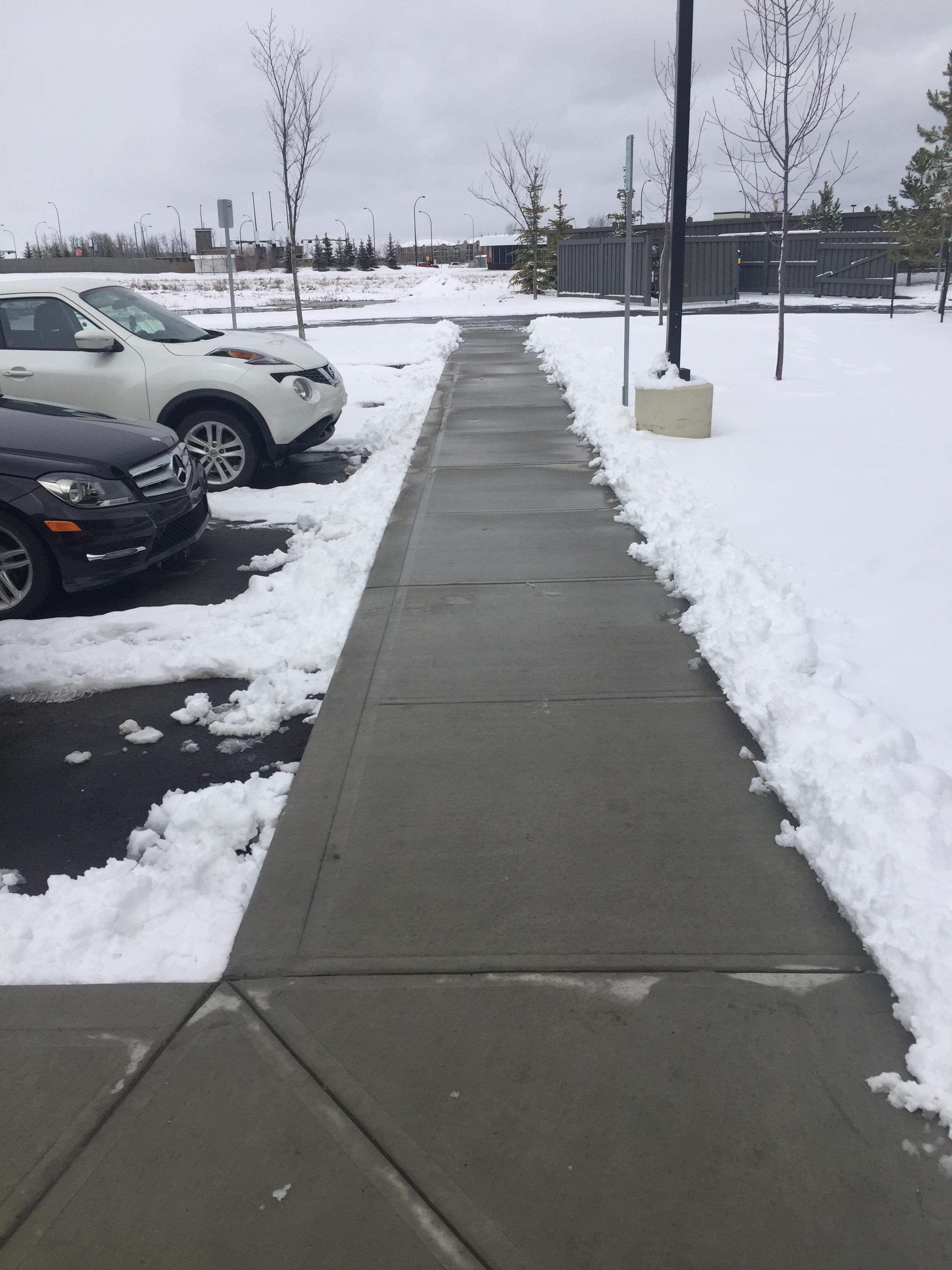 Commercial parking lot walkway cleared with apartment building in background